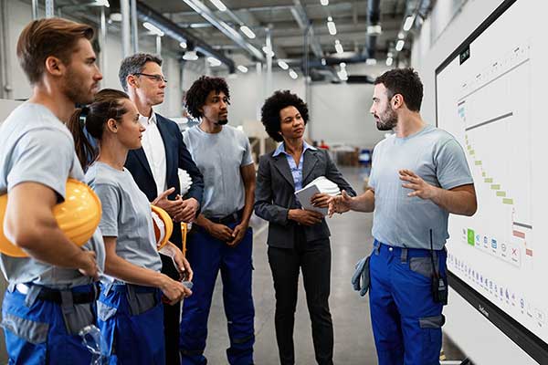 group of workers standing in front of digital smart board watching presentation